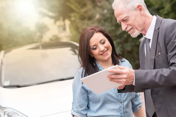 Sprzedawca samochodów, dając informacje na tablet do młodej kobiety, światło — Zdjęcie stockowe