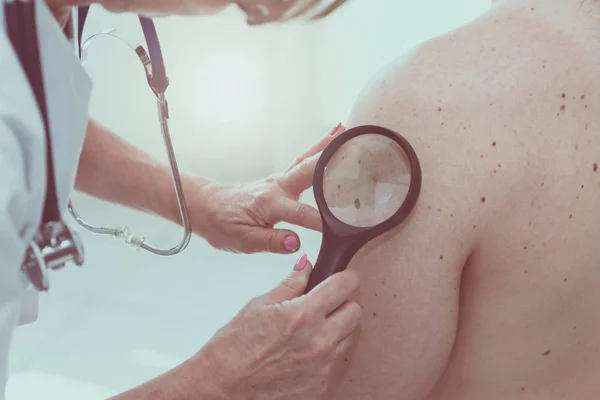Dermatologista examinando a pele de um paciente — Fotografia de Stock