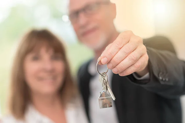 Seniorenpaar zeigt Hausschlüssel, Lichteffekt — Stockfoto