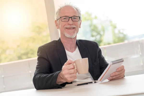 Ritratto di uomo felice con in mano taccuino e tazza di caffè, leggero — Foto Stock