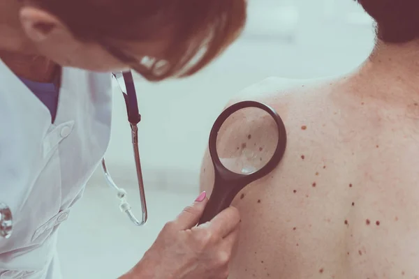 Dermatologista examinando a pele de um paciente — Fotografia de Stock