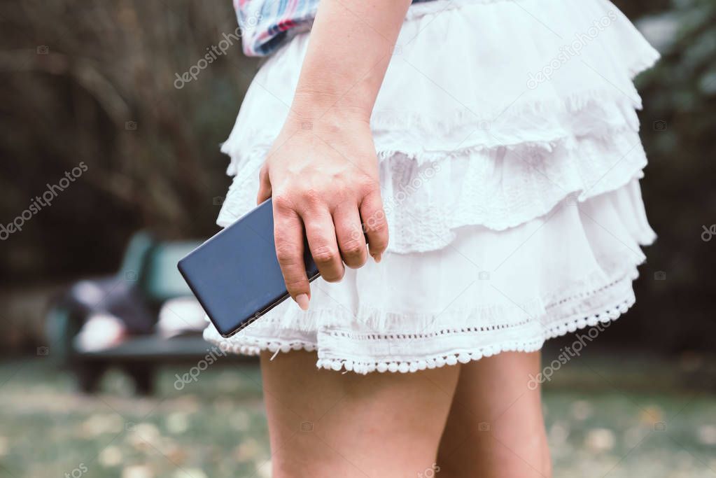 Young woman in white skirt with mobile phone in her hand