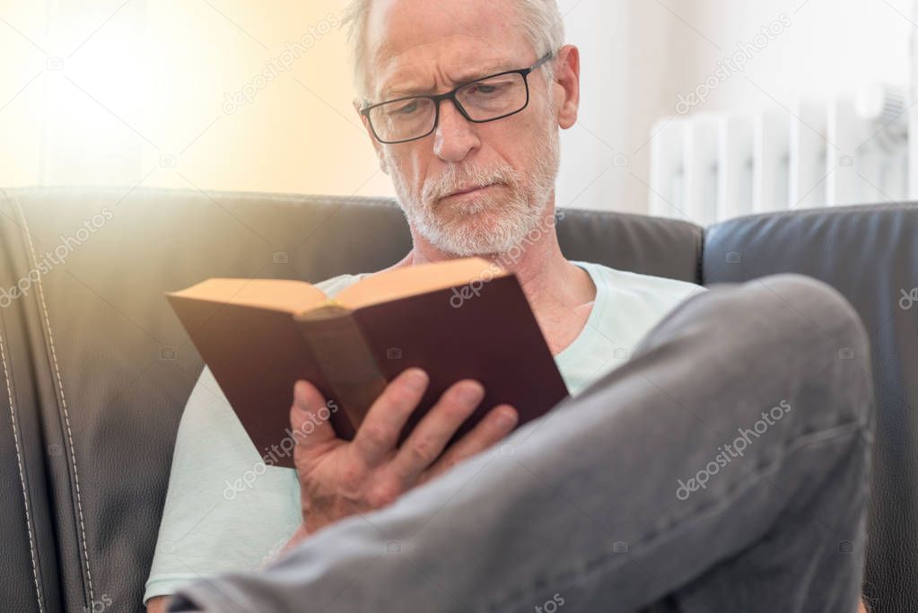 Portrait of mature man reading a book, light effect