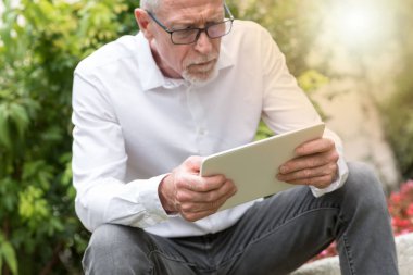 Olgun adam ışık efekti açık havada, onun tablet kullanma