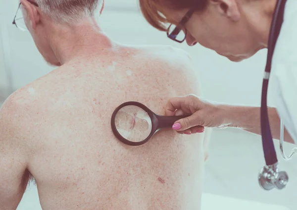 Дерматолог, осматривающий кожу пациента — стоковое фото