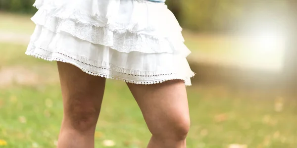 Jeune femme jambes en jupe blanche, effet de lumière — Photo