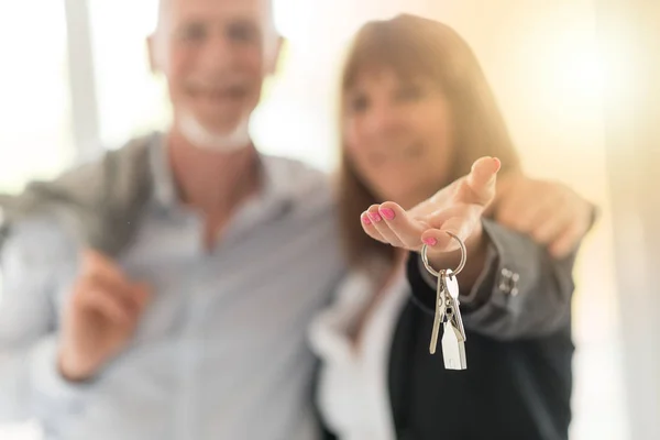 Senior couple showing house keys, light effect — Stock Photo, Image