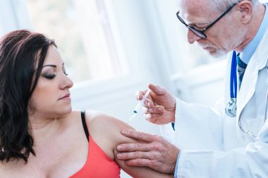 Doktor genç kadına aşı enjekte