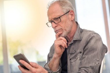 Düşünceli adam seyir onun mobil telefon, ışık efekti