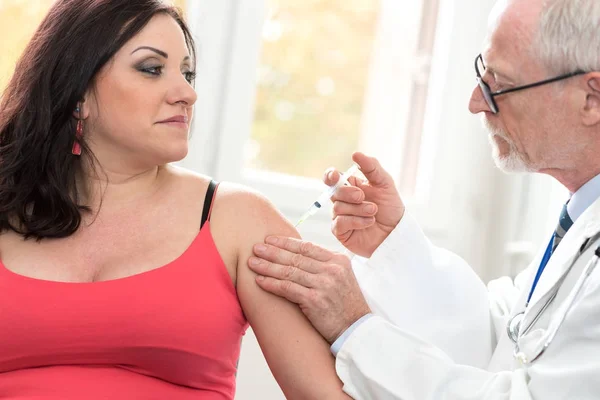 Médico inyectando vacuna a una mujer joven — Foto de Stock