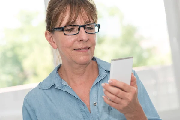 Femme mûre utilisant son téléphone portable, effet de lumière — Photo