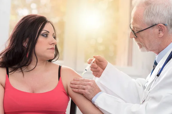 Врач вводит вакцину молодой женщине, световой эффект — стоковое фото