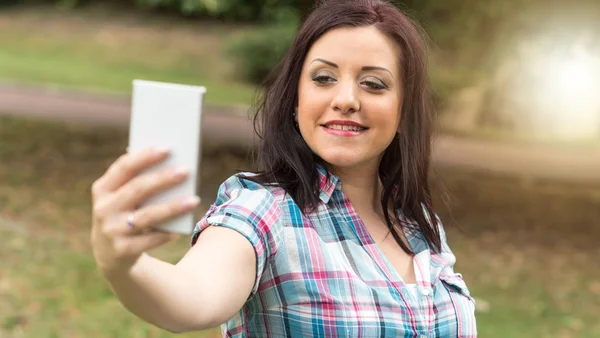 Muito jovem morena tirando uma selfie ao ar livre, efeito de luz — Fotografia de Stock