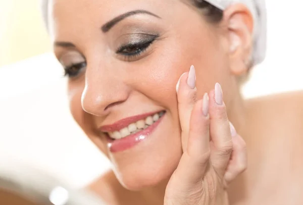 Retrato de sorrindo jovem mulher aplicando creme hidratante — Fotografia de Stock