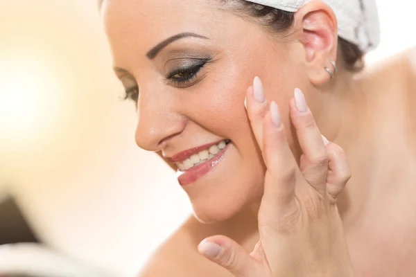 Portrait of smiling young woman applying moisturizing cream — Stock Photo, Image