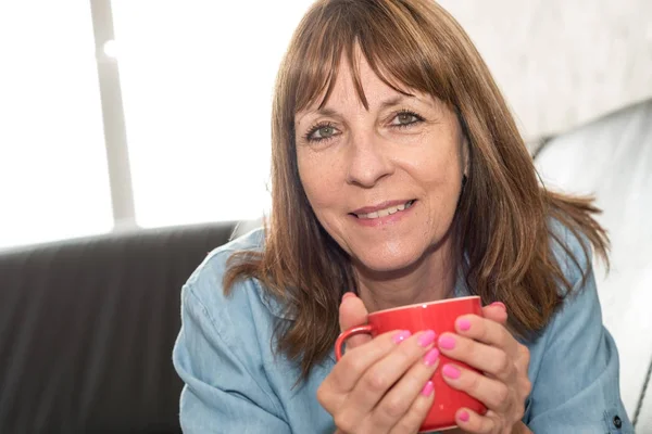 Зрелая женщина во время перерыва на кофе дома — стоковое фото
