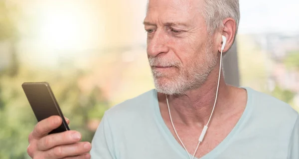 Portrett av en moden mann som lytter med øretelefoner, lys eff – stockfoto