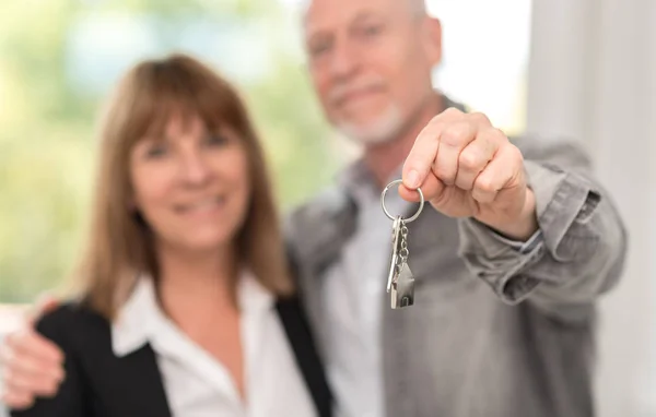 Äldre par visar hus nycklar — Stockfoto