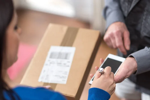 Mujer recibiendo paquete de repartidor hombre — Foto de Stock