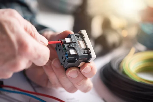 Eletricista conectando um fio em uma tomada de energia, efeito de luz — Fotografia de Stock