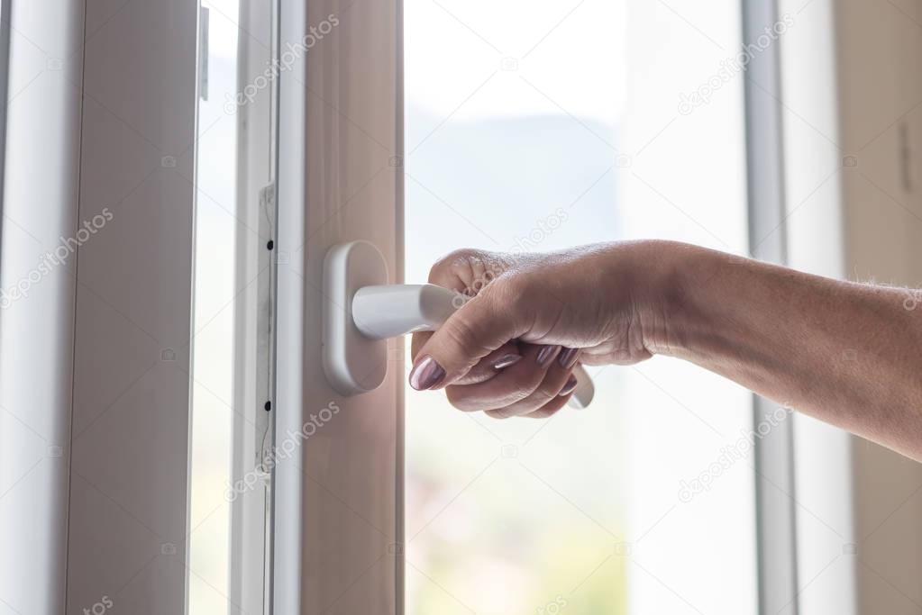 Female hand opening a window