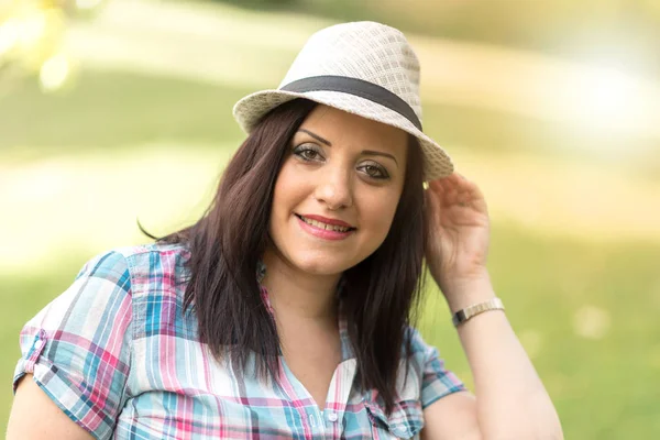 Portrait of beautiful young woman with hat in park, light effect — Stock Photo, Image