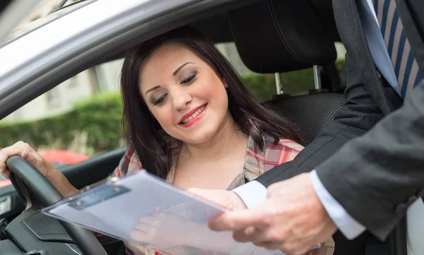 Vendedor de carro dando explicações na área de transferência para a mulher jovem — Fotografia de Stock