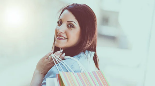 Jonge vrouw lopen met shopping tassen in de hand, lichteffect — Stockfoto