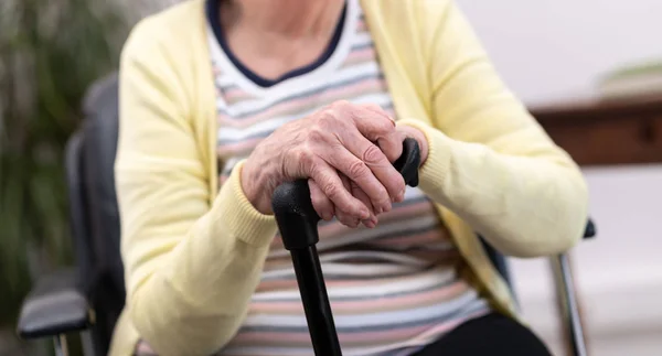 Oude vrouw met haar handen op een stok — Stockfoto