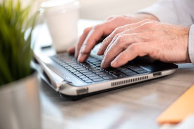 Eller dizüstü bilgisayarda klavyede yazıyor.