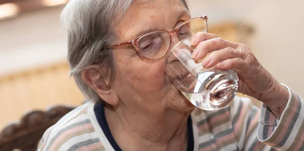 Пожилая женщина пьет воду — стоковое фото