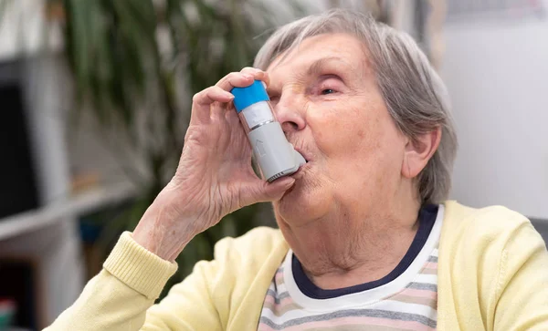 Mulher velha usando um inalador de asma — Fotografia de Stock