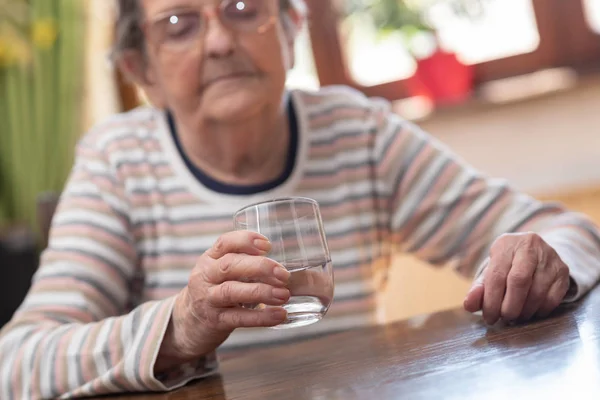 Mujer mayor sosteniendo un vaso de agua — Foto de Stock