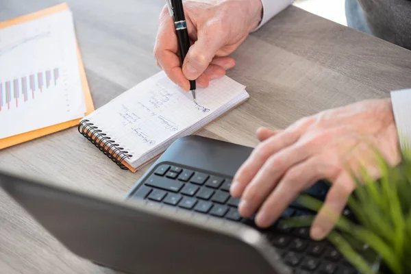 Zakenman maken van aantekeningen op laptop — Stockfoto