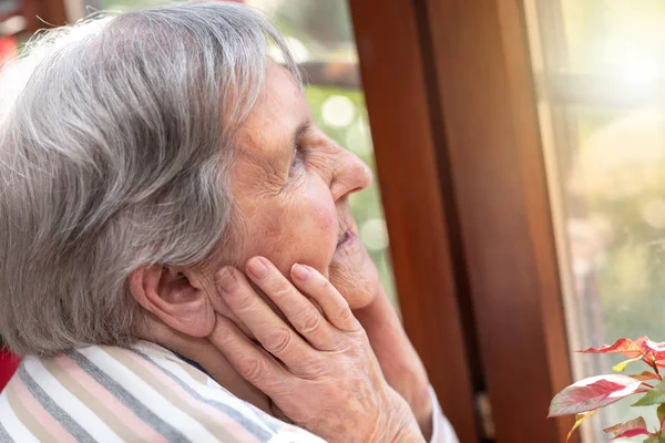 Mujer mayor mirando por la ventana — Foto de Stock