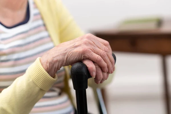 Oude vrouw met haar handen op een stok — Stockfoto