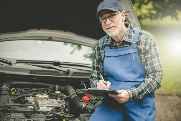 Araba tamircisi bir arabanın motorunu kontrol ediyor. — Stok fotoğraf