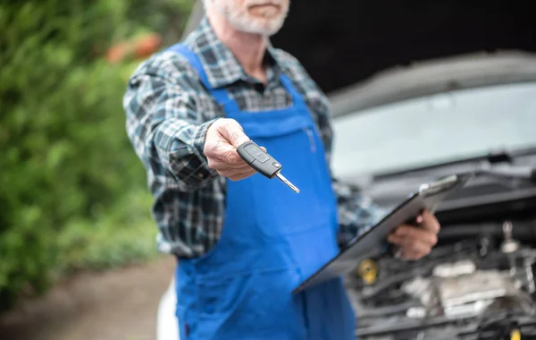 Mechanic delivering car keys after car engine checking — Stock Photo, Image