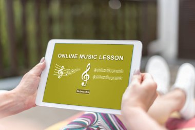 İnternette müzik dersi konsepti olan bir tableti tutan kadın eller.