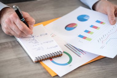 Finansal sonuçlar üzerinde çalışan ve not defterine not alan bir iş adamı