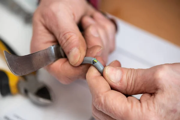 電力ケーブルの絶縁を切断する電気技師の手 — ストック写真