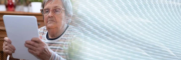 Elderly woman using a digital tablet; panoramic banner