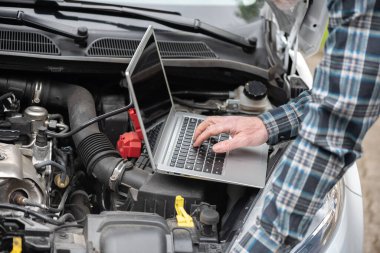 Araba motoru kontrol etmek için dizüstü bilgisayar kullanarak araba tamircisi