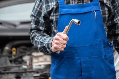 Araba tamircisi arka planda araba motoru olan araçları tutuyor