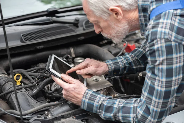 Car mechanic using digital tablet for checking car engine