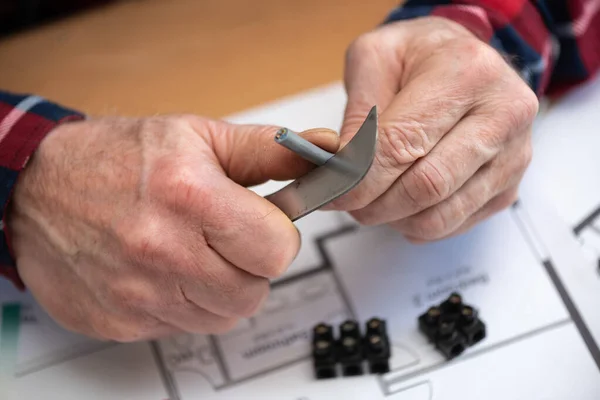 Electrician hands cutting the insulation of a power cable