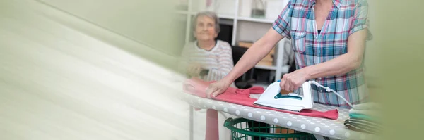 Home Helper Ironing Clothes Elderly Woman Panoramic Banner — Stock Photo, Image
