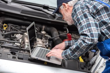Araba motoru kontrol etmek için dizüstü bilgisayar kullanarak araba tamircisi