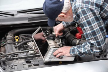 Araba motoru kontrol etmek için dizüstü bilgisayar kullanarak araba tamircisi