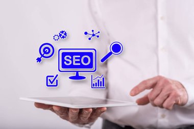 Arka planda bir adamın tuttuğu tabletin üstündeki Seo kavramı.